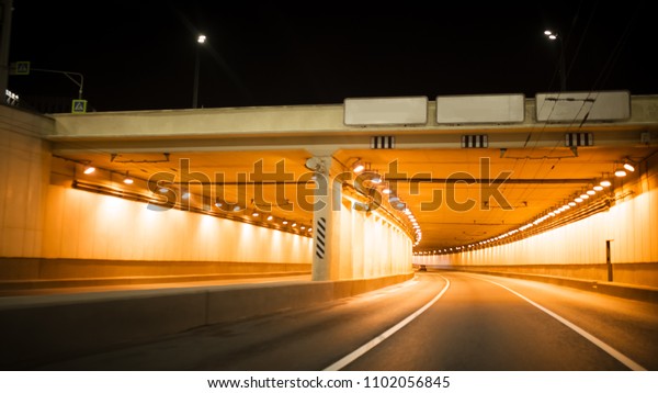 Road bridge subway underground tunnel illuminated\
at night city lights
