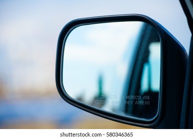 Road Car Rear View Mirror Motion Blurred Background With Warning Objects Are Bigger Than They Appear.