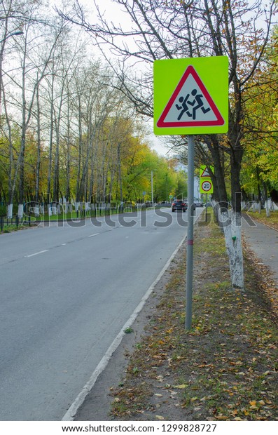 road\
with a caution sign children in the fall in the\
city