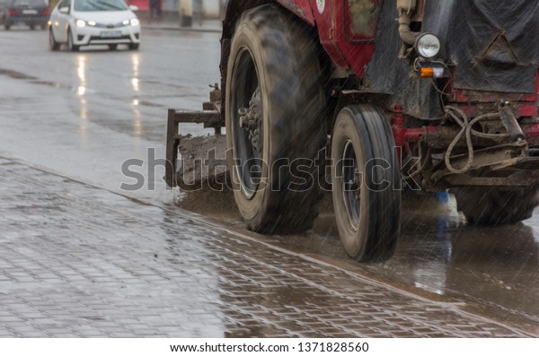 road cleaning on a tractor, a tractor\
with a brush sweeps dirt from the road, уборка дороги, трактор с\
щеткой сметает грязь с дороги, грязная дорога,\
