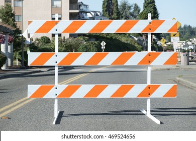 Road closed for construction barricade consisting of three horizontal bars alternating orange and white diagonal stripes and blurred background - Shutterstock ID 469524656