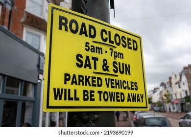 Road closed sign with black text on a yellow background attached to a lamp post on a British town centre street
