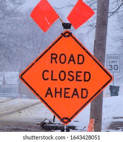 Road Closed Sign In Front Of A Snowy Road As Snow Is Still Falling