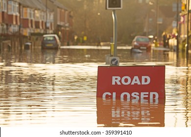 A 'Road Closed' sign partially covered in flood water lit by the evening sun - Shutterstock ID 359391410