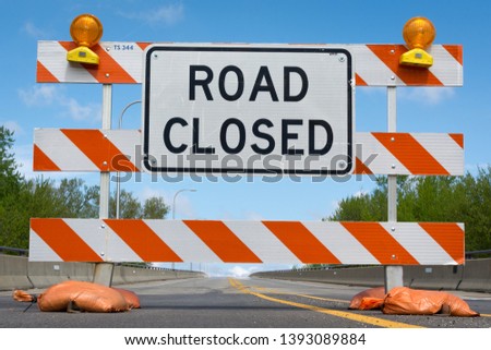 Road closed signs on a bridge over the swollen Illinois river after flooding on the roadway.
