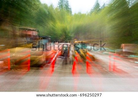 road construction equipment lined up behind a row of bollards/lens zoom creates a motion blur effect