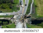 Road construction. Excavator repairing destroyed bridge after hurricane flooding water washed away asphalt in Florida. Construction equipment at roadwork site