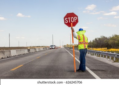 Straßenbau auf der Autobahn, Worker hält ein Stoppschild, um den Verkehr zu kontrollieren