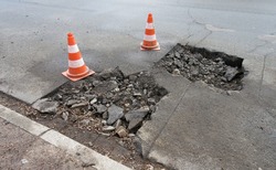 Road Construction, Road Rehabilitation, Asphalting.
Holes And Damage On An Asphalt Road, Secured By Red And White Shut-off Cones Because Of The Risk Of Accidents
