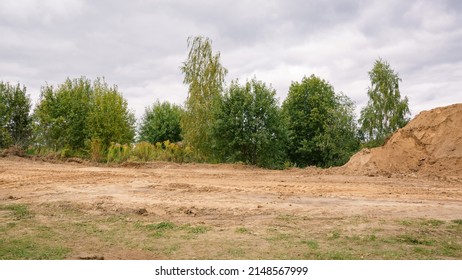 Road construction. Sand mounds and leveled land. Driveways. Creation of infrastructure. Nature landscape. Summer. Rural country road. Close-up. Copy space. Nobody. No people. Earthwork. Sand quarry.
