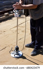 A road construction site: A worker using a transport engineering instrument, a lightweight deflectometer, for measuring subgrade and subbase layers percents of compaction