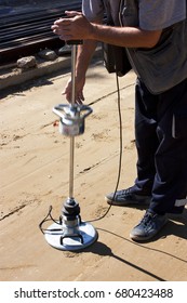 A road construction site: A worker using a transport engineering instrument, a lightweight deflectometer, for measuring subgrade and subbase layers percents of compaction