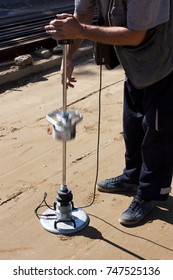 A road construction site: A worker using a transport engineering instrument, a lightweight deflectometer, for measuring subgrade and subbase layers percents of compaction of ground