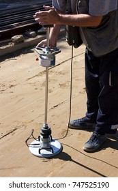A road construction site: A worker using a transport engineering instrument, a lightweight deflectometer, for measuring subgrade and subbase layers percents of compaction of ground