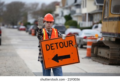 Road Construction Worker Holding A Detour Sign And Gesturing To Stop.