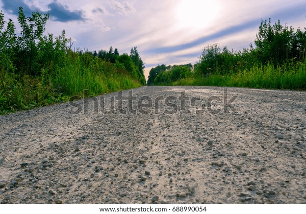 Road in the countryside,\
disappearing into the distance on the background of beautiful\
sunset