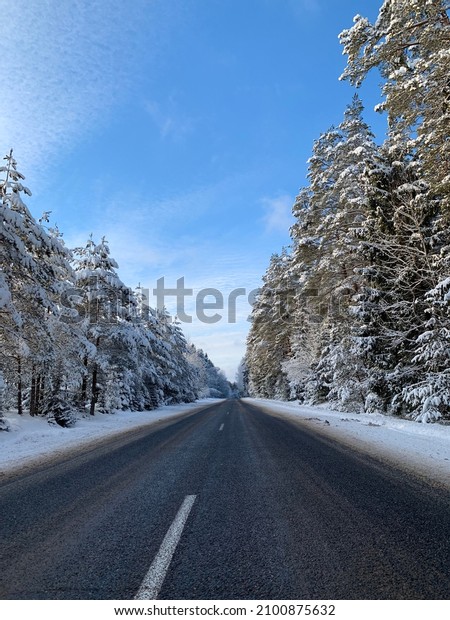 Road to the countryside in winter with forest on\
both sides
