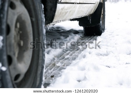 The road is covered with white snow. slippy road. Close up of a cars tires on a snowy road