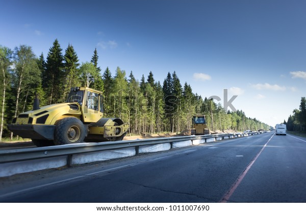 road\
with crash barriers in the forest ,guard rail on country road.\
paver on the side of the road. Construction\
area
