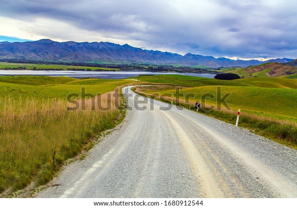 The road crosses the hills of South Island.\
Christchurch Road. The landscape of New Zealand. The hills were\
overgrown with yellowed grass. The concept of active, environmental\
and photo tourism