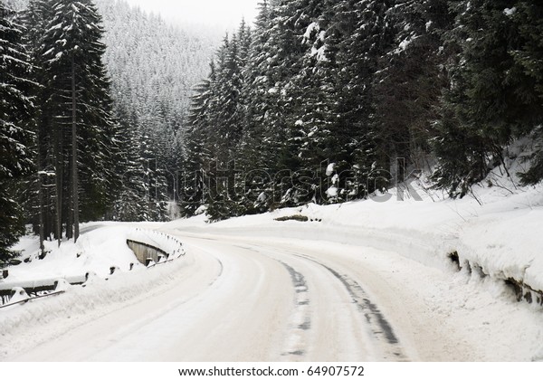 road\
curve in winter with lot of snow and snow\
barriers
