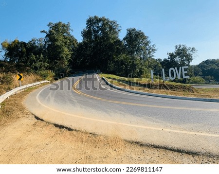 The road curves into a U-shaped shape and then has an I LOVE sign at Bo Kluea District, Nan Province,Thailand.no focus