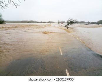 Road cut rain and floods in river flood with muddy water and some fallen tree - Shutterstock ID 2100187930