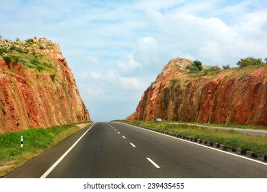 Road cutting through the hill against blue cloudy sky. A highway with no vehicles. Beautiful landscape. Incredible India. - Powered by Shutterstock