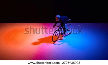 Road cyclist accelerating during intense training session in studio. Concept of speed development, reaction training, and performance optimization for competitive cycling.