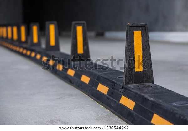 Road dividers with yellow stripes on road to\
underground garage