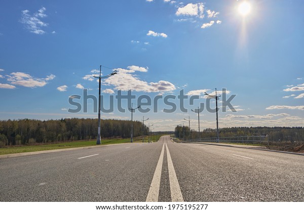 The road with a dividing strip\
that disappears into the horizon, blue sky, road trip\
concept