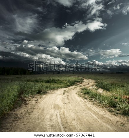 Road in field and stormy clouds