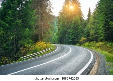 Road In Forest At Sunset In Spring. Beautiful Mountain Roadway, Trees With Green And Orange Foliage. Landscape With Empty Asphalt Winding Road Through Woodland In Autumn. Travel In Europe. Nature