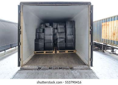 Road Freight Trailer Loaded With Boxes. Boxes Wrapped In A Black Stretch Film. Interior View Of Empty Semi Truck Lorry