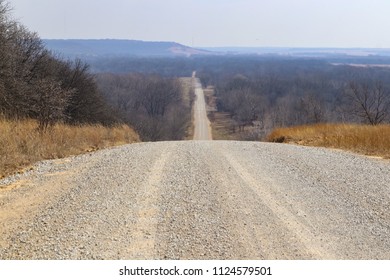 The road goes on forever - Gravel road in winter stretches over hills almost to the hazy horizon