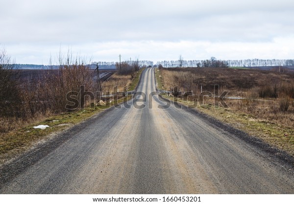 The road is going into the distance.\
Early spring. Tracks on the pavement from\
cars