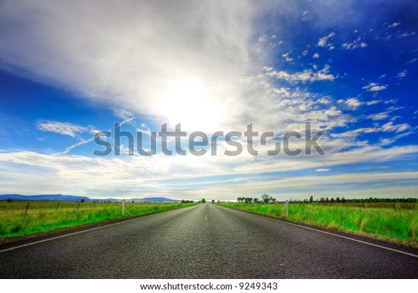 Road going straight ahead under spectacular blue\
cloudy sky