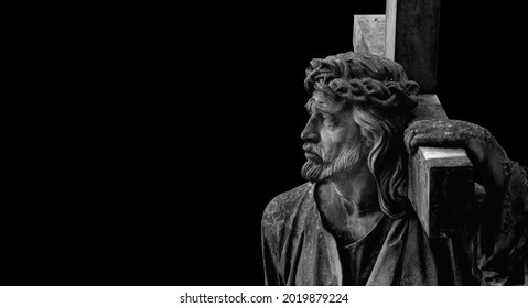 The road to Golgotha. An acient stone statue of Jesus Christ with cross. Copy space for design or text.