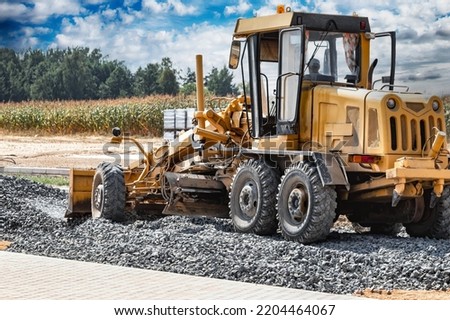 Road grader at the construction site. Powerful construction machine for ground leveling and excavation. Close-up. Professional construction equipment