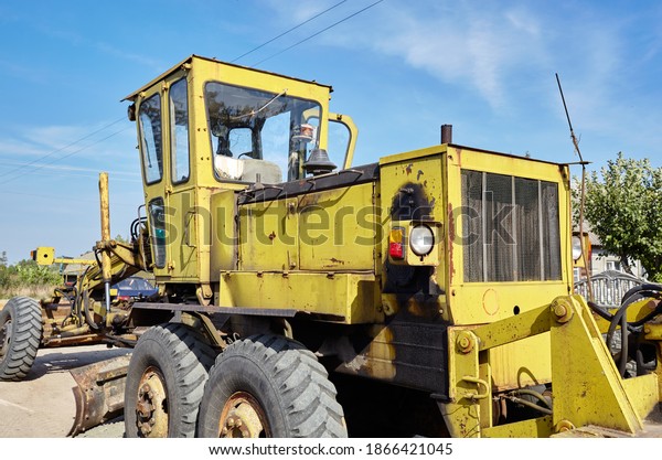 Road grader - heavy earth moving\
road construction equipment. Industrial motor grader on\
ground