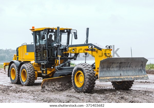 Road grader -\
heavy earth moving on dirty\
ground