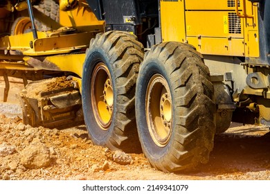 Road grader working at construction site for maintenance and construction of dirts and gravel road. Yellow motor grader. Heavy machinery and construction equipment for grading roads. Grader machine.