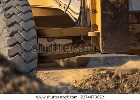 Road grader working at construction site for maintenance and construction of dirts and gravel road. Yellow motor grader. Heavy machinery and construction equipment for grading roads. Grader machine.