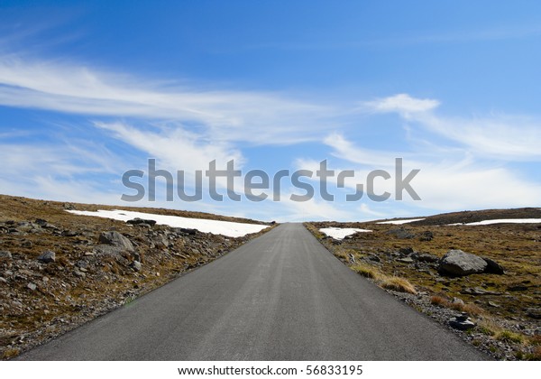 road to heaven. Empty road receding\
into the distance and the blue sky at the\
background