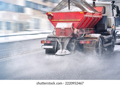 Road and highway maintenance gritter truck spreading de-icing salt on road in winter. Salt spreading. Snow plow service truck removing snow and spreading salt on snowy city road during blizzard