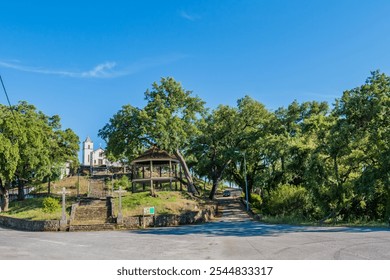 Road with hill and green trees with staircase flanked by crosses with bandstand and church in the background, Pedrogão Grande PORTUGAL - Powered by Shutterstock