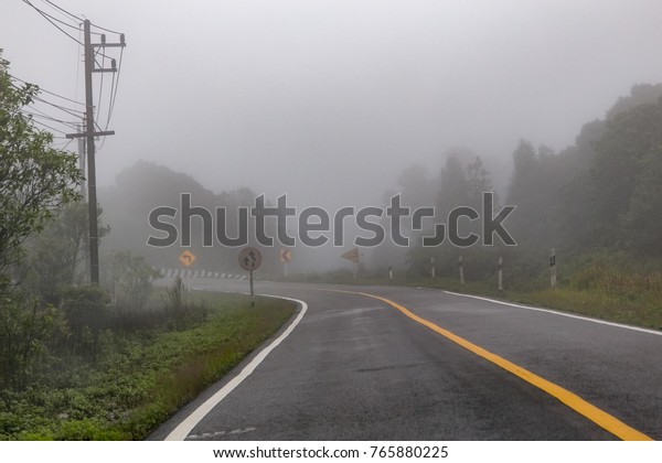 The\
road up the hill with mist and trees along the\
way.