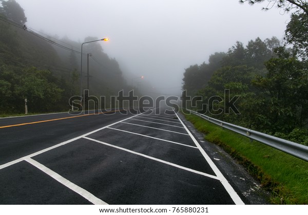 The\
road up the hill with mist and trees along the\
way.