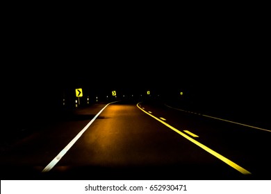 Road Into The Dark With Curve Sign At Night