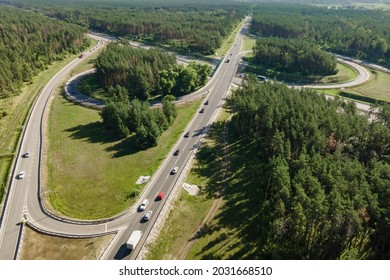 Road junction intersection with car traffic transportation in forest near city, aerial view